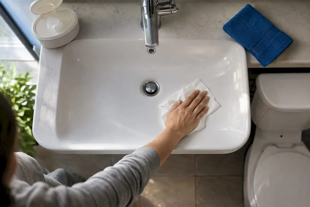 Hand wiping an apartment bathroom sink